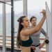 Female fitness coach writes on whiteboard as a male athlete watches in a gym.