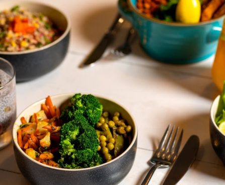 Delicious colorful bowls of salad and fresh beverages on a white table, perfect for healthy dining.